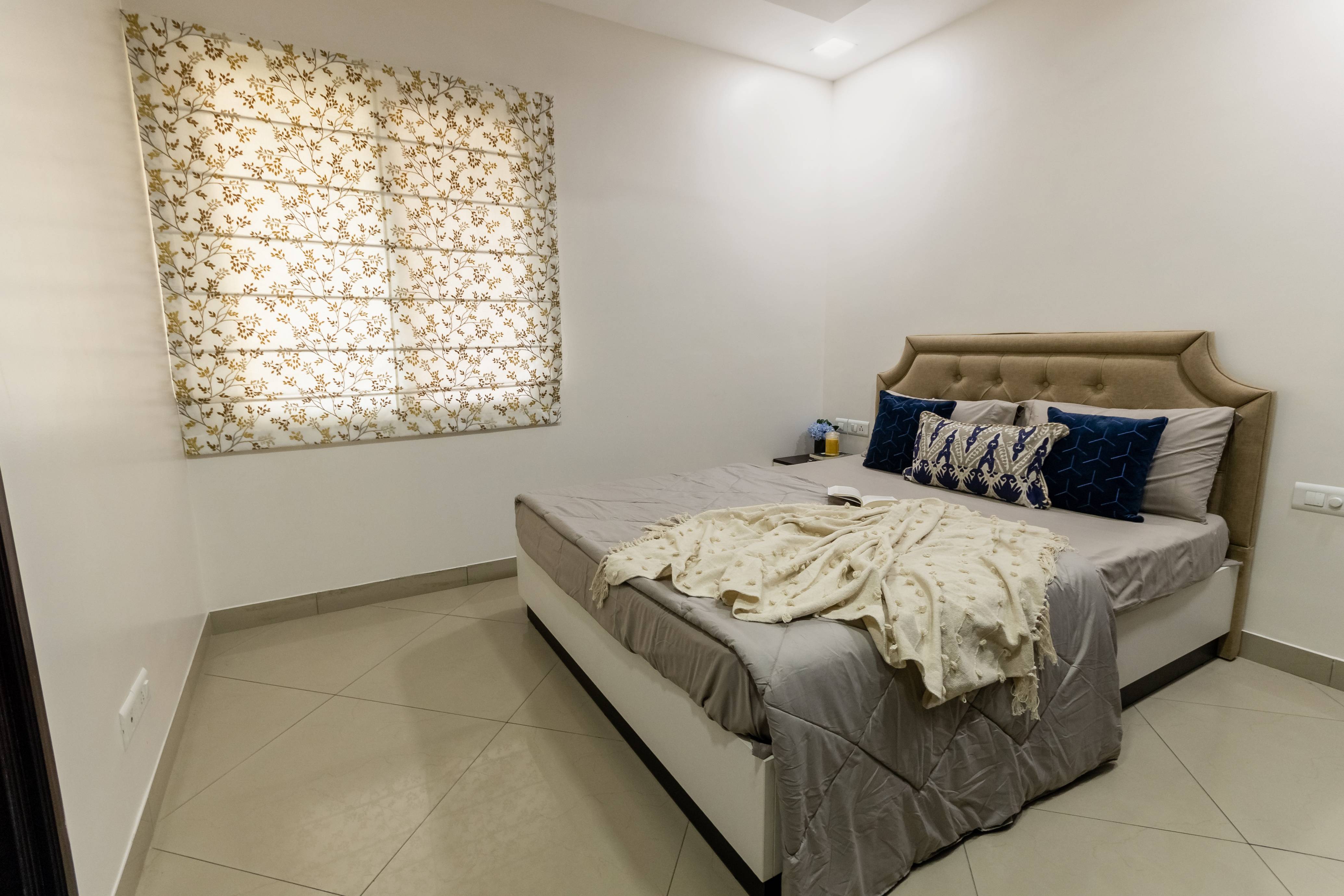 Spacious Guest Bedroom Design With Beige Tufted Headboard | Livspace